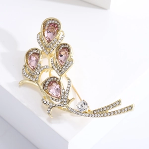 Detailed view of pink pear-shaped crystal Calla Lily brooch with gold plating and white stones