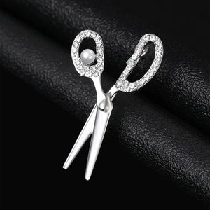 Macro detail of scissor brooch with sparkling rhinestones and pearl on black leather