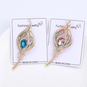 Detailed macro of gold peacock feather brooches with colorful rhinestones and enamel inlay
