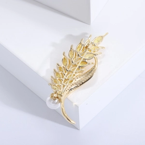 Detailed macro view of gold wheat ear brooch with yellow zircons and white pearl inlay