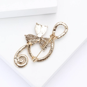 Close-up of golden music note brooch with metallic texture on a white pedestal