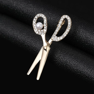 Detail of gold scissor brooch with sparkling rhinestones and a white pearl accent