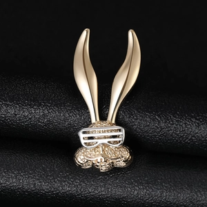 Close-up of golden long-eared rabbit brooch with silver glasses on black leather background
