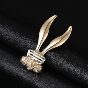 Detail of golden bunny brooch with silver glasses and inlaid zircon on black leather