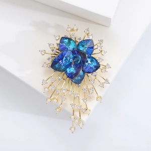 Macro shot of gold floral brooch with blue heart crystals and white cubic zirconia details
