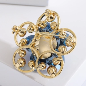 Vue détaillée du dos d'une broche fleur dorée avec cristal bleu et fermoir à épingle