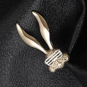 Macro shot of creative golden long-eared rabbit brooch with silver goggles on leather