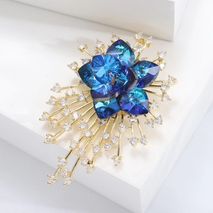 Elegant flower brooch with blue crystal petals and zircon accents on golden metal stems