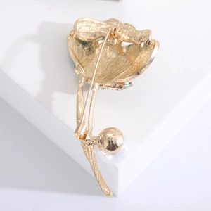 Detail view of golden water lily brooch with brushed texture and white pearl accent