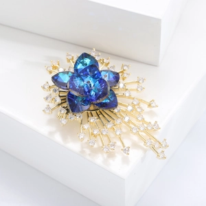 Detailed macro view of the gold-plated crystal flower brooch with blue zirconia petals