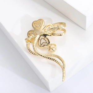 Détail du dos d'une broche fleur dorée montrant le fermoir de sécurité et la gravure