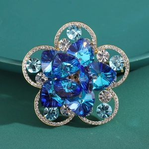 Makroaufnahme einer eleganten Goldblütenbrosche mit blauen Kristallen und weißen Diamanten