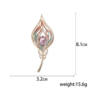 Golden feather brooch with pink gemstone and enamel accents, size 8.1cm by 3.2cm