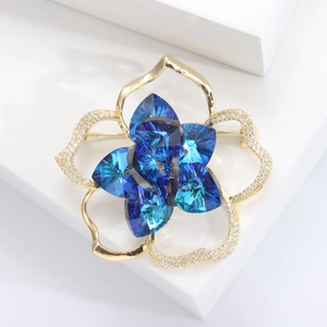 Macro detail of camellia brooch with blue crystals and gold-plated floral petals