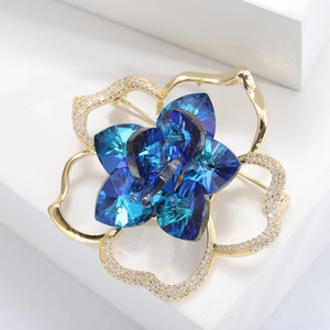 Elegant gold flower brooch with deep blue crystals and white cubic zirconia accents