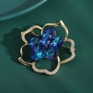 Elegant gold flower brooch featuring deep blue crystal center and sparkling zircon petals