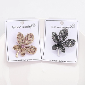 Detailed macro of two rhinestone maple leaf brooches in pink and purple colors