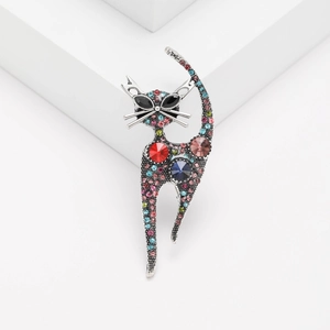Vintage silver cat brooch with colorful rhinestones on a minimalist white geometric display