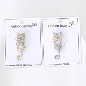 Detailed view of cat brooches with rhinestones and bows on jewelry display card