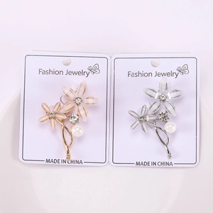 Vue détaillée de deux broches florales ornées de strass et de perles blanches nacrées