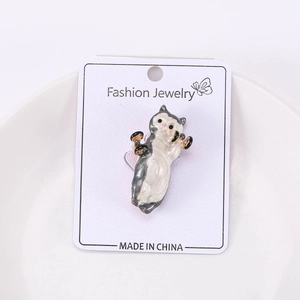Detail of creative enamel cat brooch holding dumbbells on a white display card