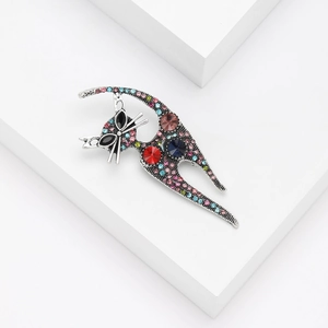 Detail of vintage cat brooch featuring colorful rhinestones and large gemstones on white cube