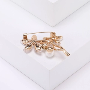 Vue détaillée de l'arrière d'une broche feuille dorée avec perle et détails en cristal