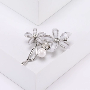 Détail de la broche fleur avec pétales en acrylique blanc, perles et strass sur métal argenté