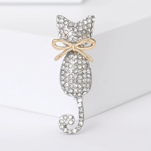 Detailed macro view of silver cat brooch with pavé rhinestones and a gold bow accessory
