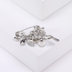 Détail d'une broche fleur argentée avec cristaux clairs et incrustation de perle blanche