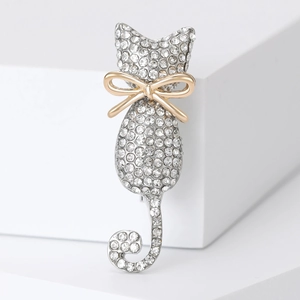 Macro shot of elegant silver cat brooch with sparkling rhinestones and golden bow