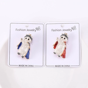 Detalle de dos pines de esmalte de gatos con coronas y capas en tarjeta de joyería moda