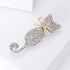 Exquisite silver cat brooch with crystal rhinestones and a gold bow on a white stone