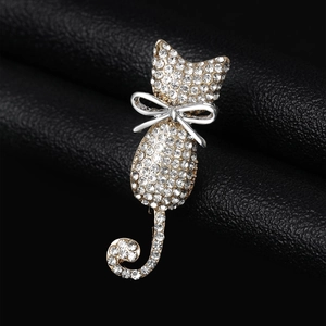 Detailed macro shot of a gold cat brooch with sparkling white rhinestones on black leather