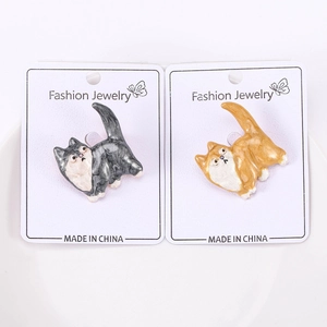 Détail de deux broches en émail en forme de chat avec texture marbrée sur carte blanche
