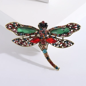 Detailed macro view of vintage dragonfly brooch with green rhinestones and bronze texture