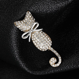 Close-up of cat brooch with sparkling rhinestones and silver bow on black leather background