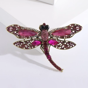 Detail of vintage gold dragonfly brooch with magenta rhinestones and hollow wings