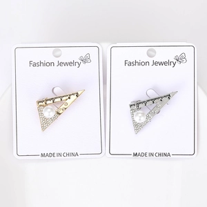 Detail of silver and gold triangle ruler brooches with small rhinestones and a white pearl