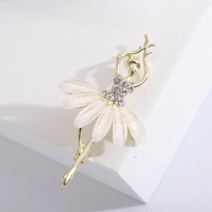 Détail d'une broche danseuse dorée avec strass scintillants et pétales blancs sur socle