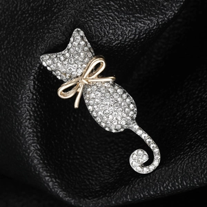 Macro shot of silver cat brooch with a gold bow tie on black leather texture