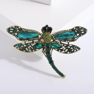 Macro detail of antique gold dragonfly brooch with emerald rhinestones and hollow wings