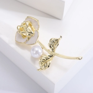 Detailed close-up of a golden camellia brooch with white enamel petals and central pearl