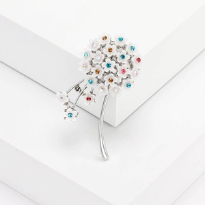 Floral dandelion brooch with colorful rhinestones on a minimalist white display