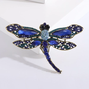 Vintage dragonfly brooch with blue rhinestones and bronze alloy finish on white background