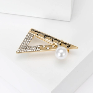 Detailed view of golden alloy set square brooch with rhinestones and pearl pendant