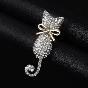 Macro shot of silver cat brooch with white rhinestones and a gold bow on black leather