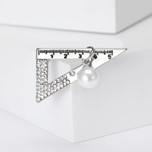 Detailed macro view of silver ruler brooch featuring clear rhinestones and a white pearl
