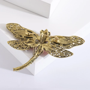 Detail view showing the bronze hollow wings and safety pin on the dragonfly brooch back