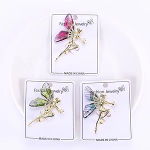 Détail de trois broches de fées colorées avec des cristaux et des perles blanches
